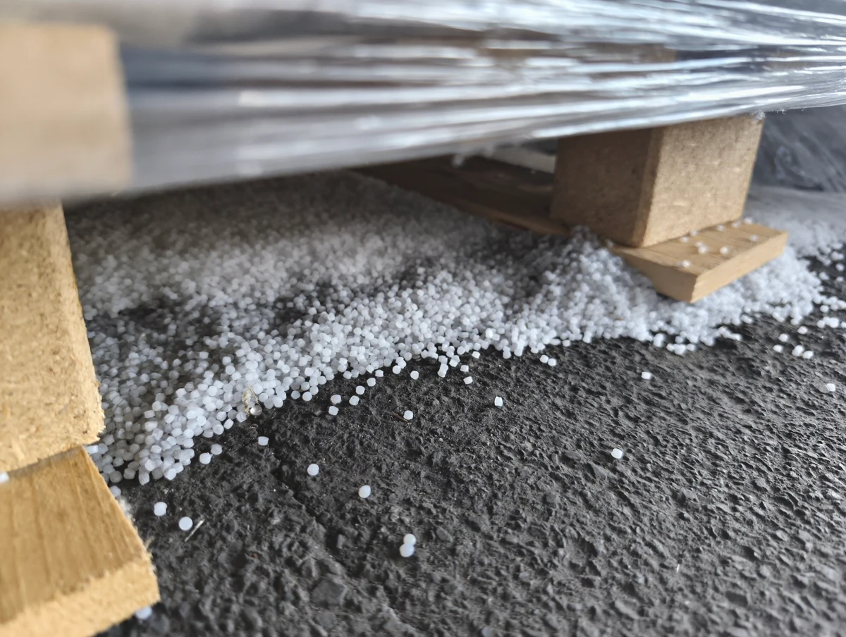 Real white plastic pellets scattered beneath a wooden pallet